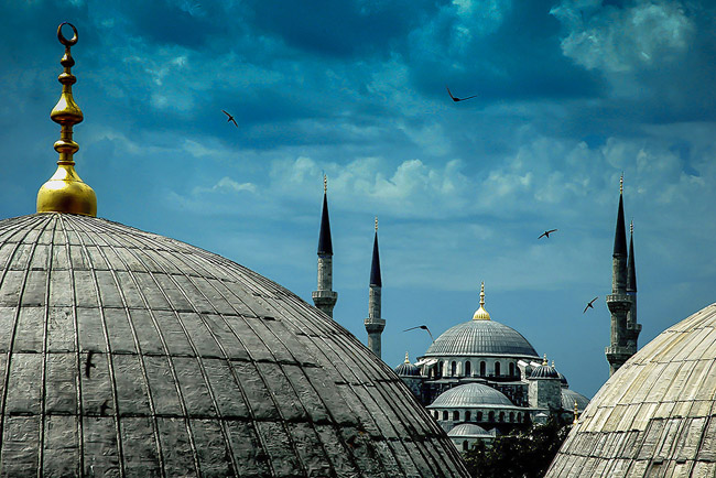 《舞者》作者：林铭述，拍摄于土耳其蓝色清真寺。长焦压缩之后的时空里，清真寺半圆的银顶，格外柔美。而在乌蓝的天空之下，飞鸟，在利剑般的塔尖之间，一次次潇洒地划出诗行般的影子。